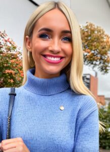 Die blonde Tally schaut mit strahlendem Lächeln in die Kamera.